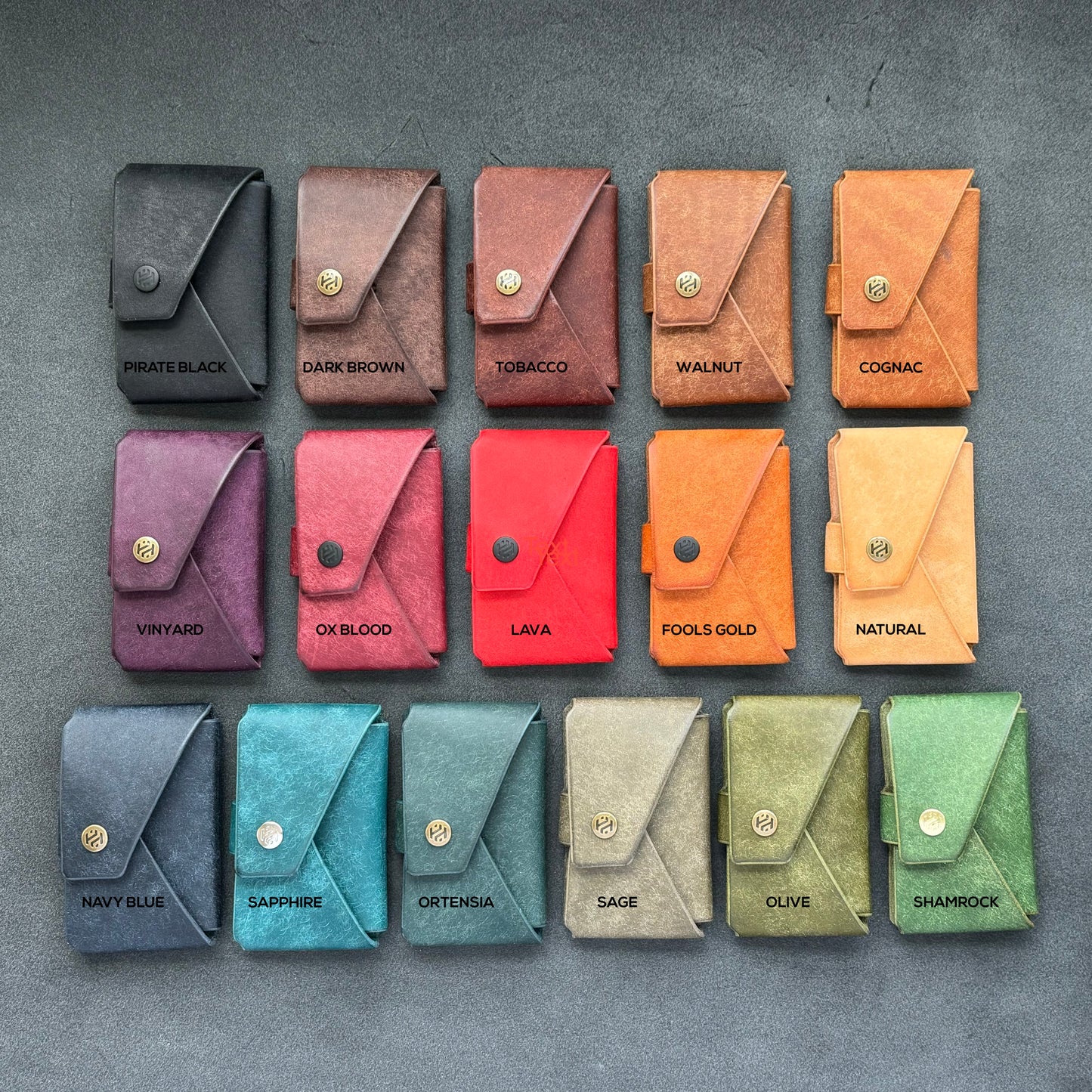 Sixteen minimalist leather wallets in a variety of colors, arranged in a grid on a flat surface.